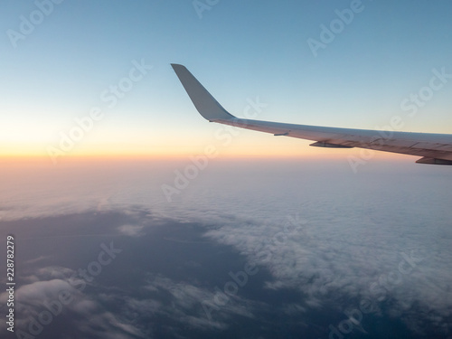Looking outside Comertial Airplane at Sunrise with White Clouds in the horizon