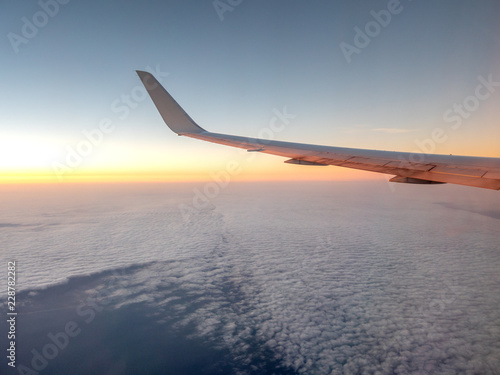 Sunrise Casting Orange tones onto Left Wing of Airplane at High Altitude