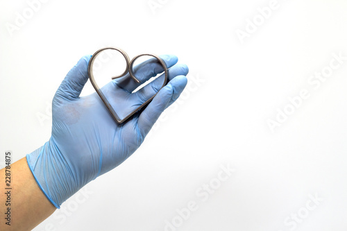 The surgeon's hand in a blue medical glove holds an iron heart .