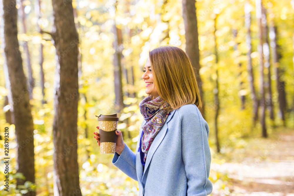 Attractive woman holding a cup of takeaway coffee cup on autumn street Attractive woman holding a cup of takeaway coffee cup on autumn street