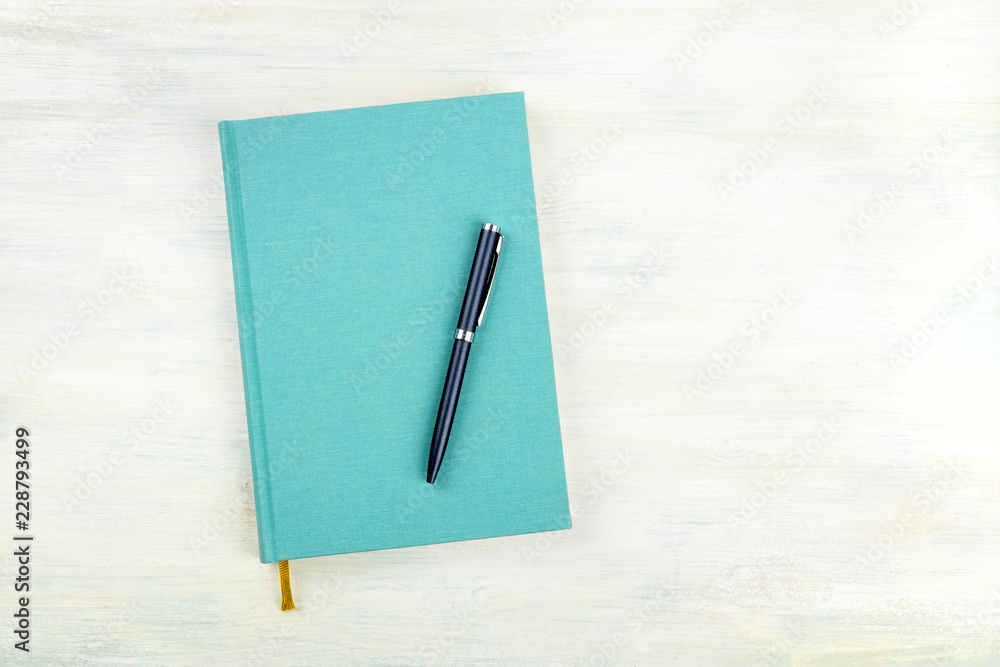 An overhead photo of a teal blue journal with a pen, an elegant notebook or planner with a place for text An overhead photo of a teal blue journal with a pen, an elegant notebook or planner with a place for text