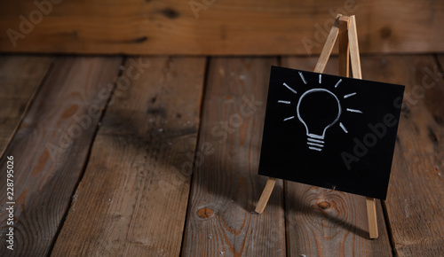 Idea concept. Light bulb drawn on a chalkboard, dark wooden background