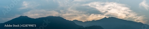 panorama mountain landscape in silhouette with wispy cloudy sky in the blue hour