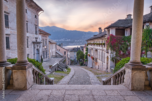 Beautiful scenic alley with historic and traditional houses and cobbled street at sunset. Picturesque Italian village, Orta San Giulio (street Albertoletti), on lake Orta, north Italy photo