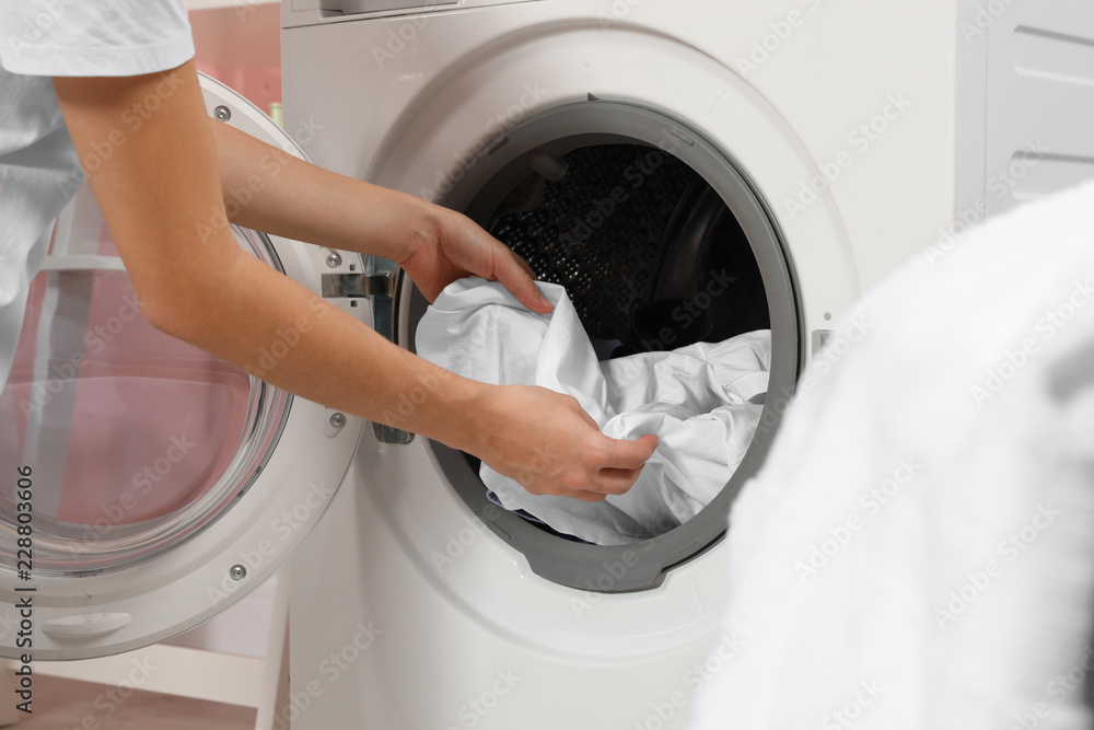 Woman taking laundry out of washing machine indoors, closeup Woman taking laundry out of washing machine indoors, closeup