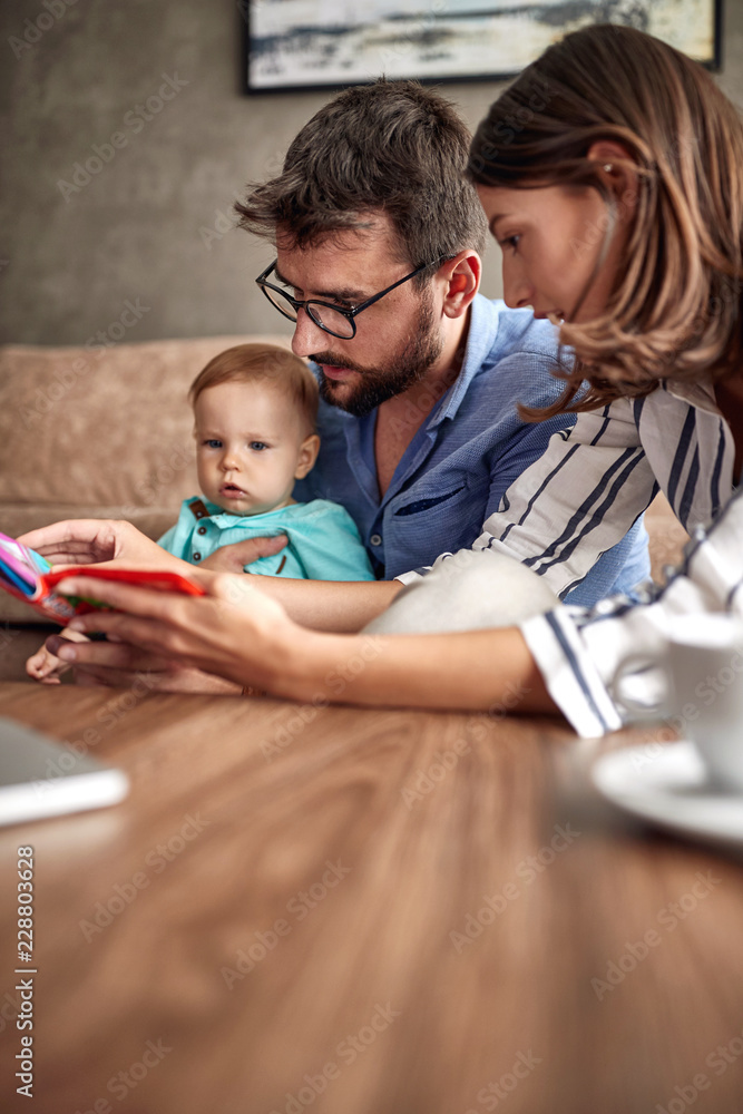 Baby boy playing with parents. Family time together reading a children book.. Baby boy playing with parents. Family time together reading a children book..