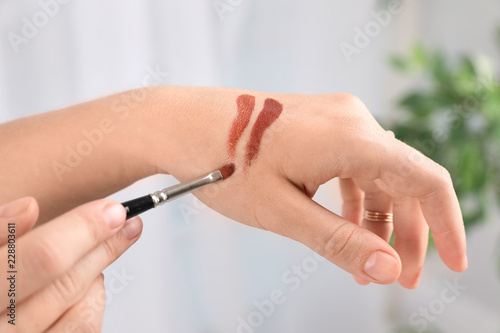 Woman testing and choosing lip gloss color on hand, closeup