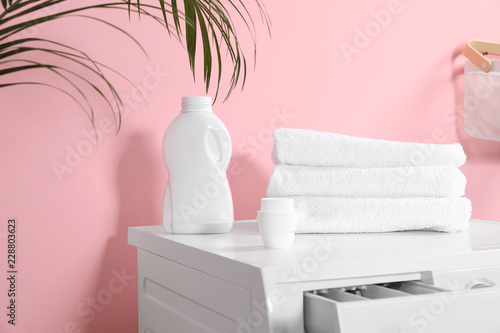 Bottle with detergent and clean towels on washing machine in laundry room