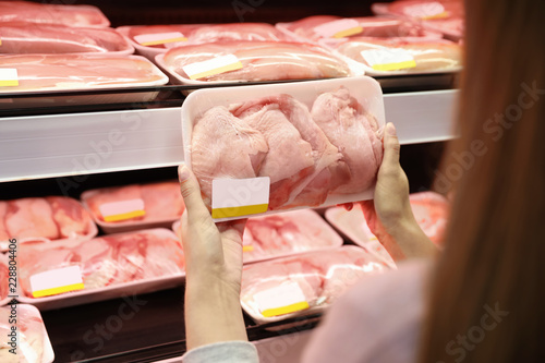 Woman choosing packed chicken meat in supermarket