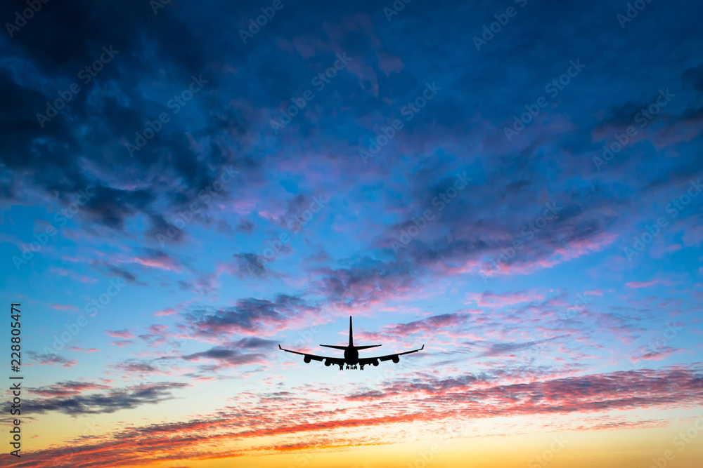 Naklejka premium Colorful bright sunset with flying airplane silhouette