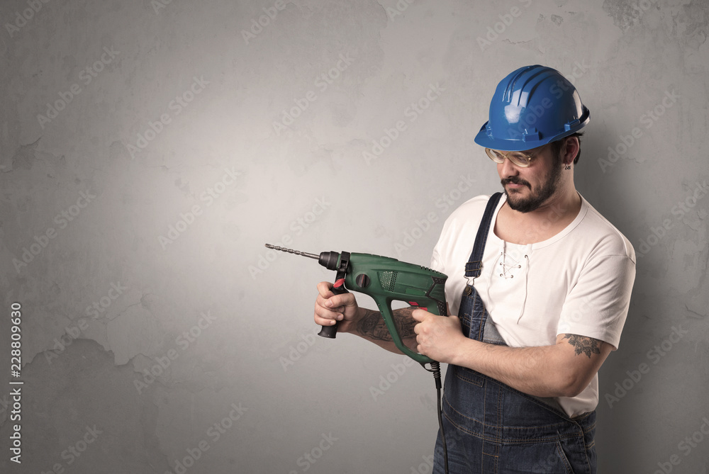 Craftsman standing in front of an empty wall with tool in his hand. Craftsman standing in front of an empty wall with tool in his hand.