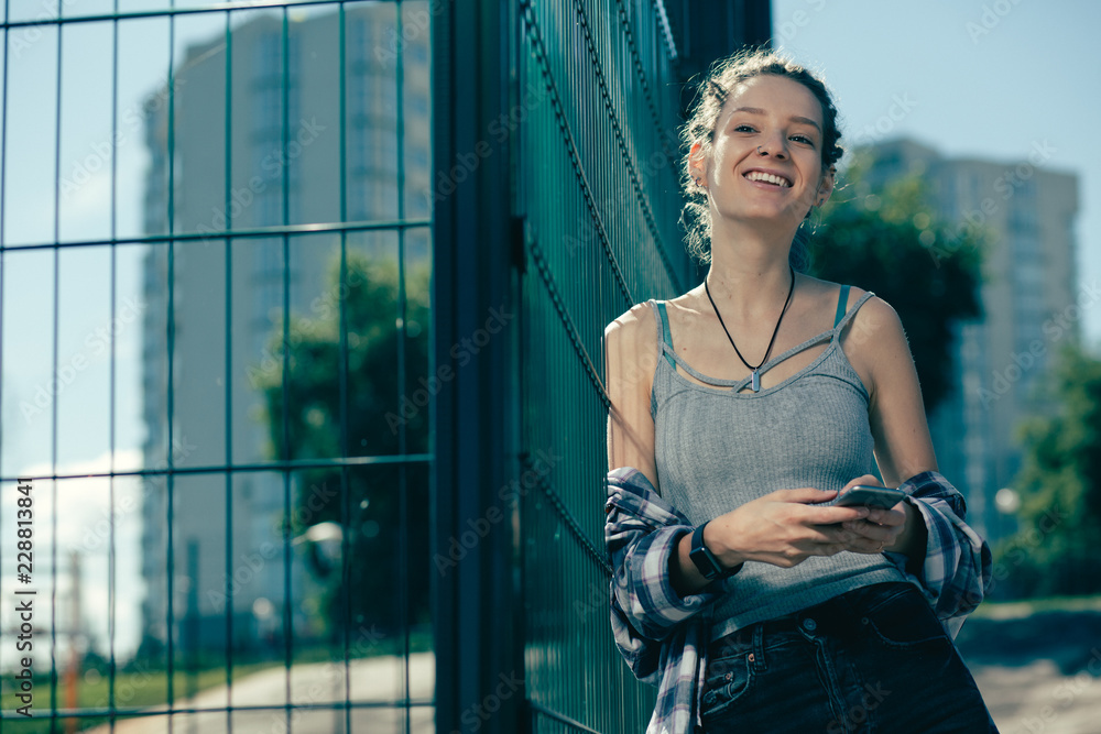 Fototapeta premium Relaxed lady laughing while standing with her smartphone