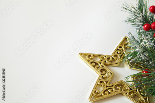 Fir tree branches, red berries, golden decorations on white background. Christmas backdrop.