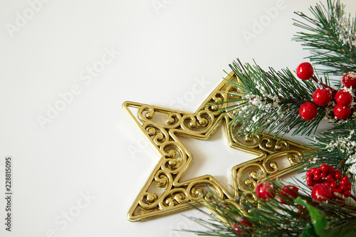 Fir tree branches, red berries, golden decorations on white background. Christmas backdrop.