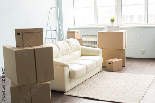 Obraz na plátně Relocation, new home and real estate concept - Moving boxes and sofa in empty ro