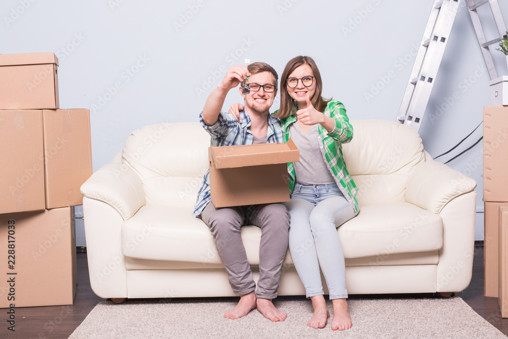 Moving, relocation and new home concept - young couple having fun on the couch surrounded with boxes Moving, relocation and new home concept - young couple having fun on the couch surrounded with boxes