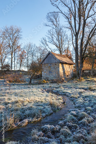 Old shed at meadow with a stream at a cold autumn morning photo