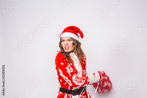 Christmas, emotions and people concept - angry woman in santa claus clothes holding presents on white background