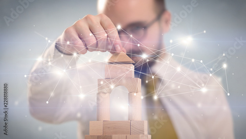 Young handsome businessman using wooden building blocks with interconnected lines and dots around him