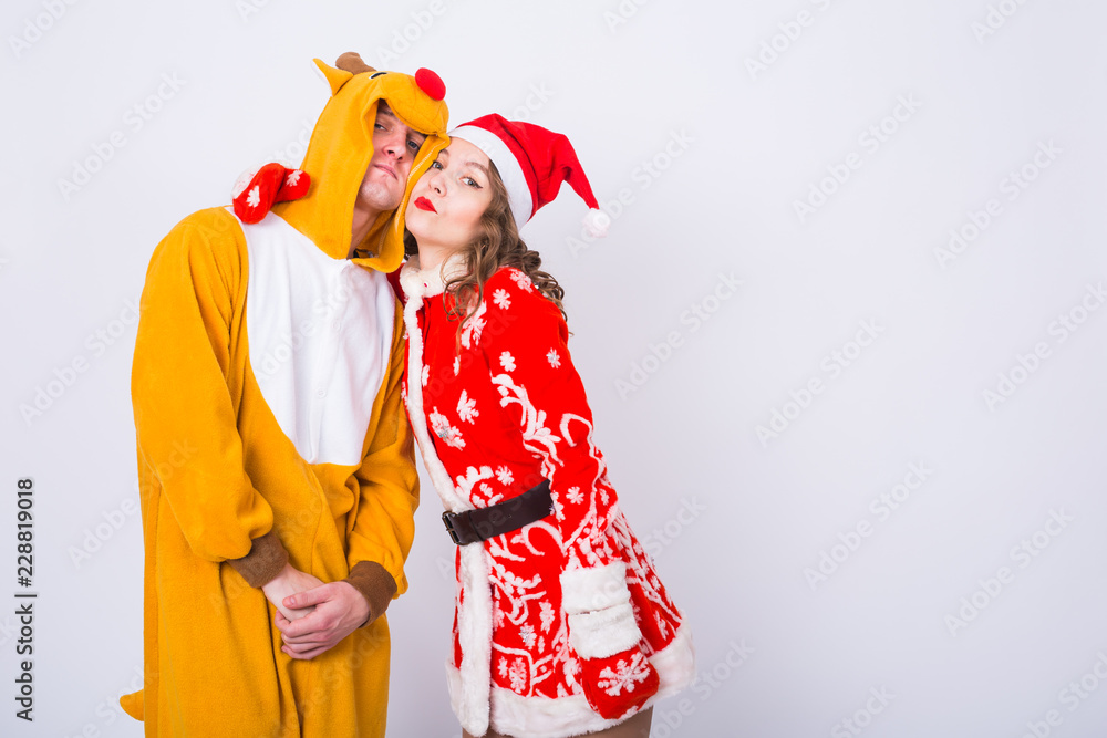 Holiday, Christmas and carnival concept - Funny couple in deer costume and Santa Claus costume have fun on white background with copy space