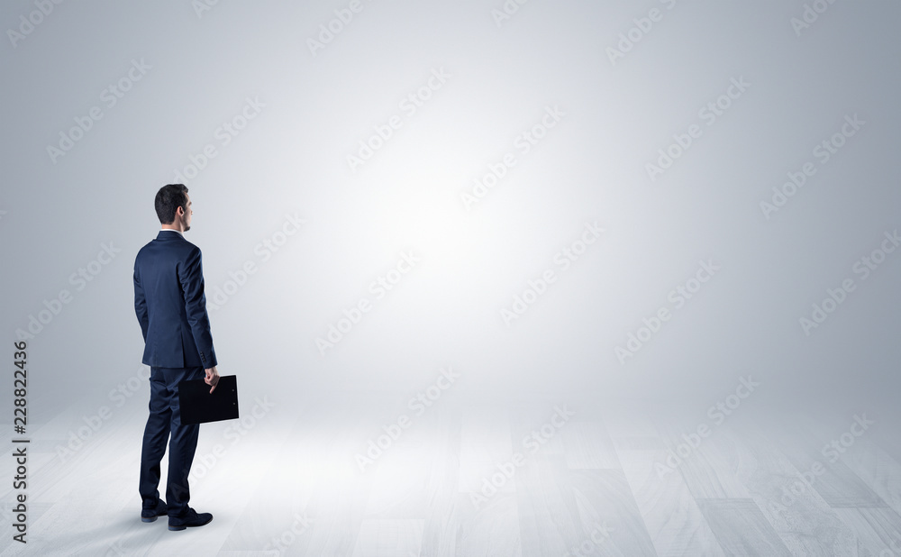 Man standing with his back in an empty room with object in his hand Man standing with his back in an empty room with object in his hand