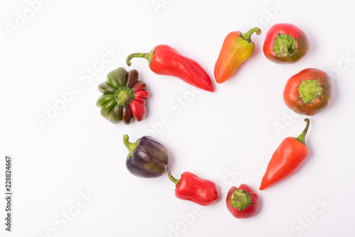 Several ripe sweet and hot peppers of red and orange on a white background