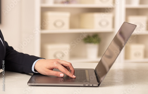 Business woman below chest working on her laptop in a cozy environment 