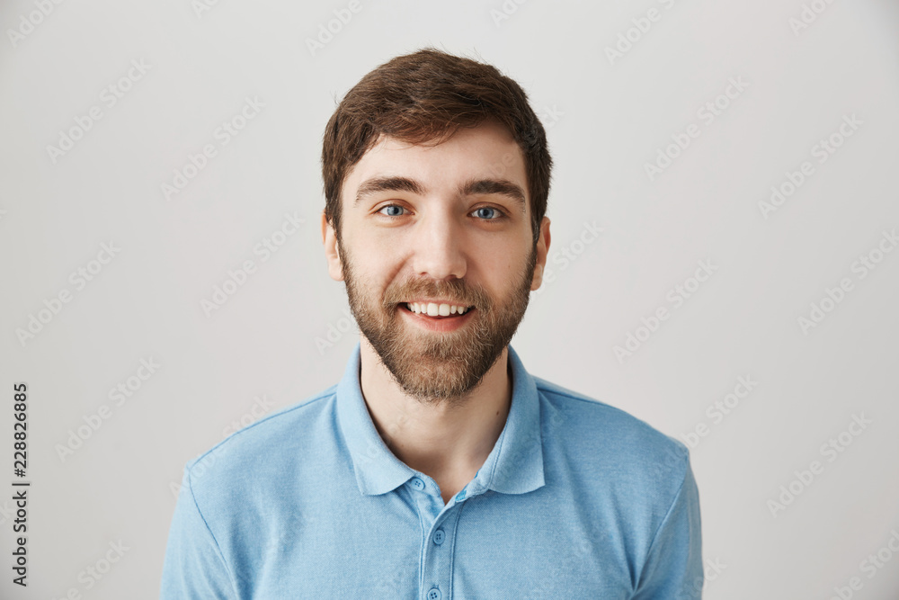 Waist-up shot of funny emotive adult bearded guy in blue polo shirt, making faces, smiling broadly and glancing with popped eyes over gray background. Man looks at delicious cake in shop with desire Waist-up shot of funny emotive adult bearded guy in blue polo shirt, making faces, smiling broadly and glancing with popped eyes over gray background. Man looks at delicious cake in shop with desire