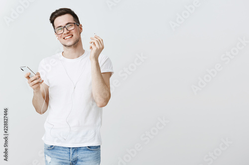 Cuadro en lienzo Guy taking off one earbud to hear what friend asked smiling joyfully liking new