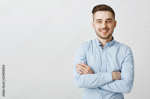 Confident and friendly handsome ambitious man with bristle in blue collar shirt holding hands crossed on chest in self-assured pose smiling joyfully intirigued to listen new idea how gain clients