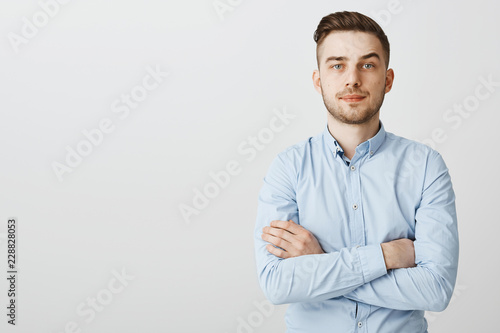 Slika na platnu Smart ambitious and serious-looking young businessman in blue collar shirt holdi