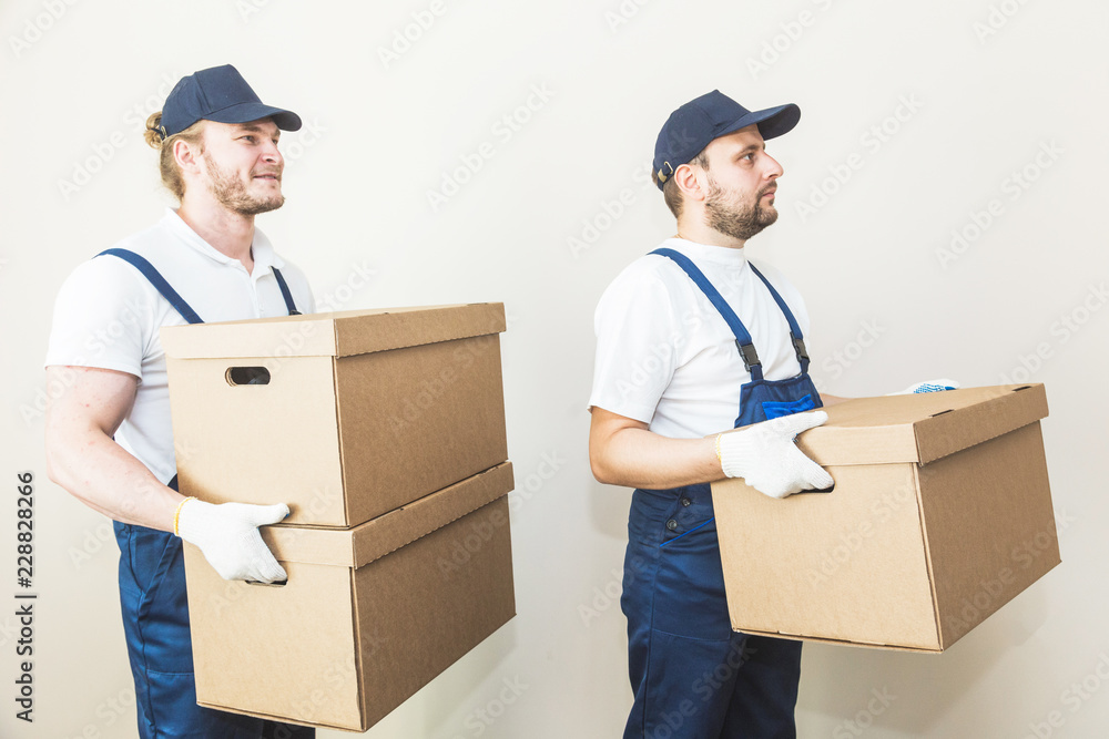 Delivery man loading cardboard boxes for moving to an apartment. professional worker of transportation, male loaders in overalls Delivery man loading cardboard boxes for moving to an apartment. professional worker of transportation, male loaders in overalls