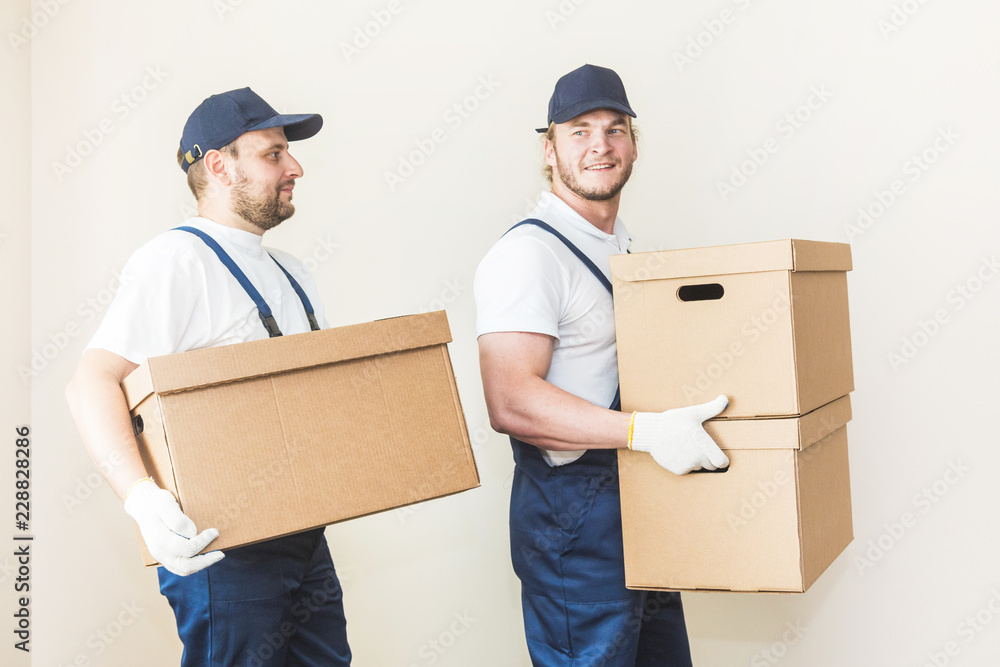 Delivery man loading cardboard boxes for moving to an apartment. professional worker of transportation, male loaders in overalls Delivery man loading cardboard boxes for moving to an apartment. professional worker of transportation, male loaders in overalls