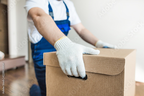 Cuadro en lienzo Delivery man loading cardboard boxes for moving to an apartment