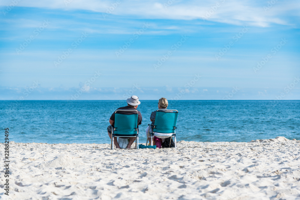 senior couple on the beach. Obese tourists, couple sitting on chairs on the beach and looking at the blue, turquoise sea senior couple on the beach. Obese tourists, couple sitting on chairs on the beach and looking at the blue, turquoise sea