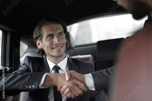 handshake of business partners sitting in the car © ASDF