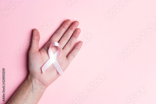 Girl hand holding pink breast cancer awareness ribbon.Copy space for text or design.