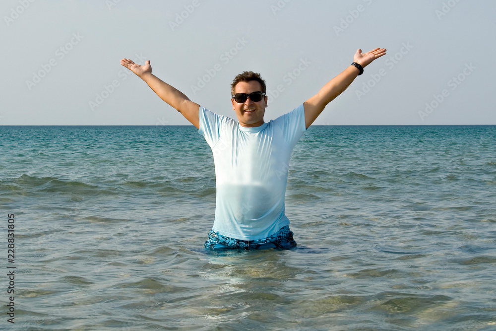 tanned man jumping out of the sea with splash