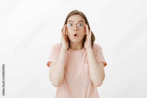 Wow, I can see clearly now. Surprised and thrilled cute european girl in pink t-shirt, putting on glasses and saying wow with folded lips, staring at camera, visiting optician and fixing sight