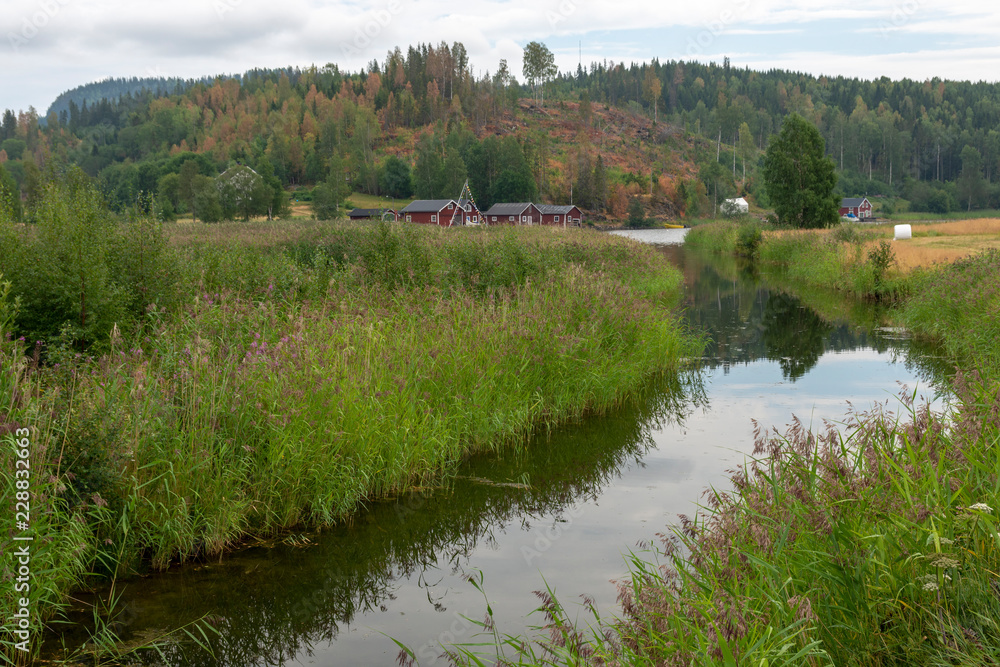 Little calm river with reflections in the vater and hill with forest in background Little calm river with reflections in the vater and hill with forest in background