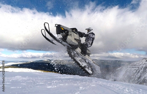 RIDER JUMPING WITH SNOWMOBILE BETWEEN CLOUDS photo