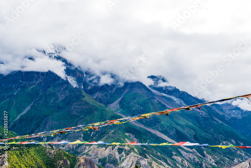 Traditional buddhist prayer flags over foggy mountain background in Ngawal, Nepal