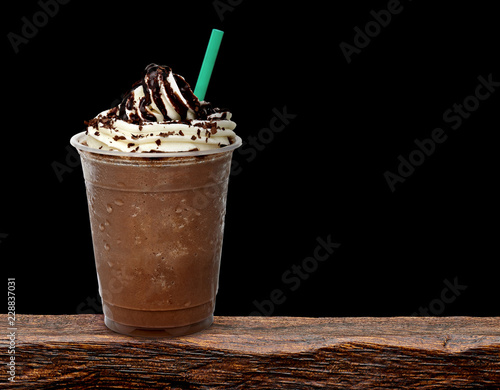 Frappuccino in takeaway cup on wooden table isolated on black background photo