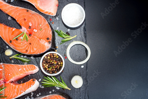 salmon steak, pepper and salt, herbs on black stone concrete table, copy space top view