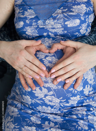 Hands of husband and woman on the belly of a pregnant woman.