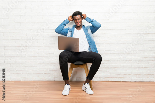 Afro american man working with his laptop unhappy and frustrated with something. Negative facial expression