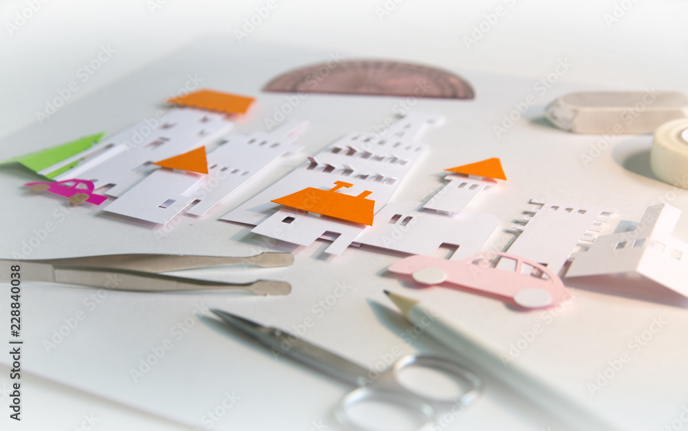Fototapeta premium Paper cut design elements with tools: scissors, knife, pare, glue etc. Creation a city view in progress. Creativity, education, hobby, innovation and inspiration concept.