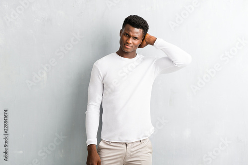 Young afro american man posing on textured grey wall
