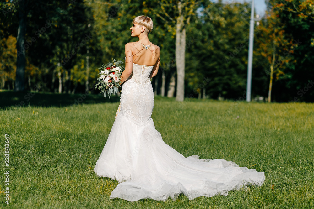 fashionable bride with short hair with a big bouquet posing in the park fashionable bride with short hair with a big bouquet posing in the park