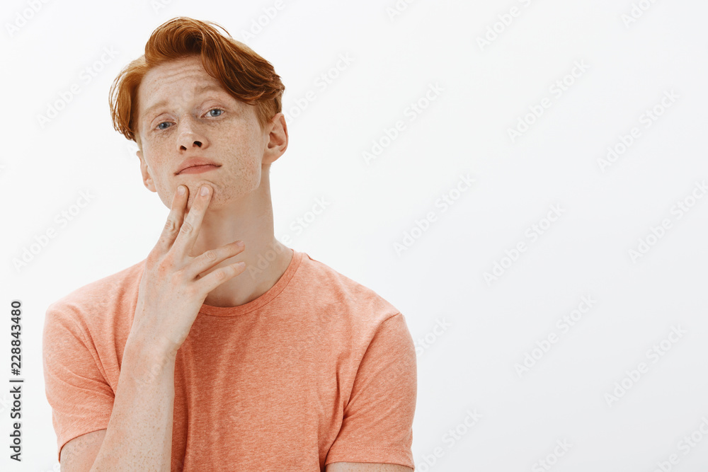 Charming stylish european ginger male with freckles, touching chin and  gazing at camera, picking clothes in wardrobe to go on party, making choice  or decision, thinking with focused calm expression Stock Photo